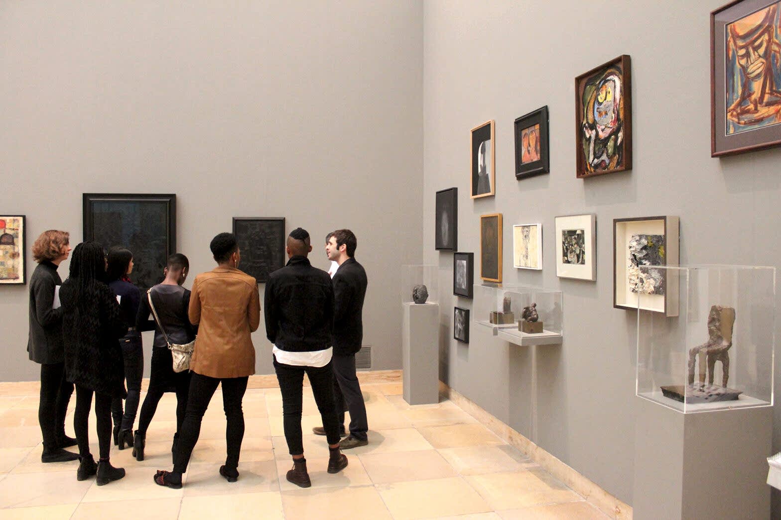 Some people in an art gallery, hacving a discussion rather than looking at artwork.
